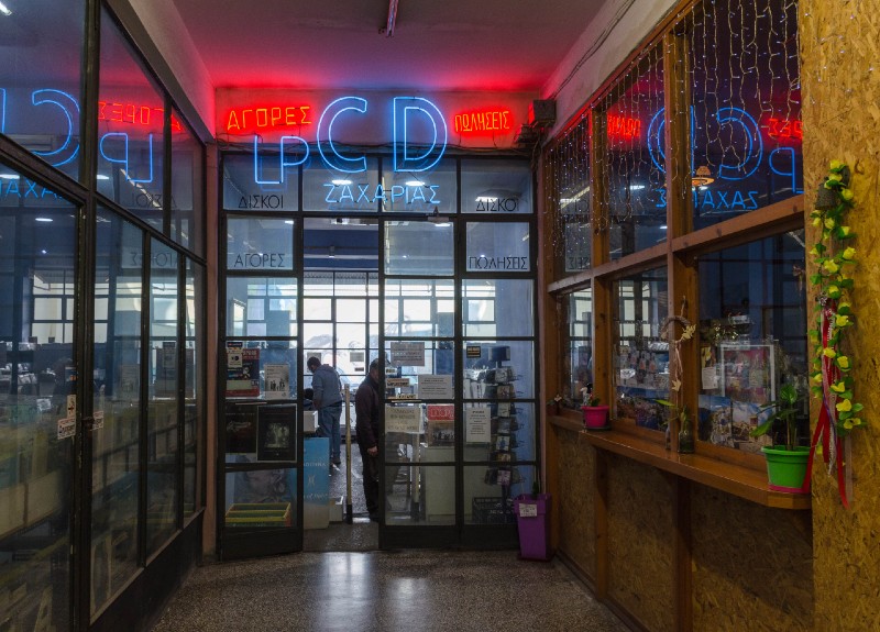 Entrance of a vintage vinyl record shop with neon signs on Ifestou Street in Athens, Greece.