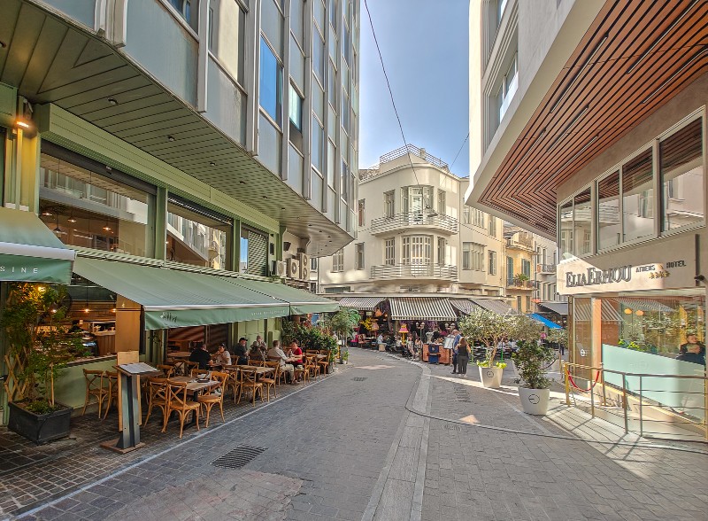 View of side street near Syntagma Square in Athens with outdoor cafés, shops, and people walking