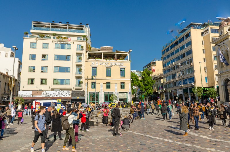 Where to Stay Near Monastiraki - Busy Monastiraki Square with hotels, cafes, and people in Athens