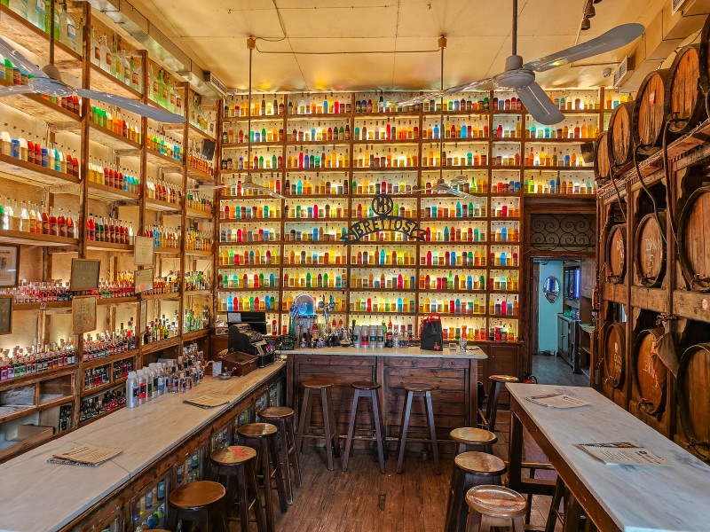 Landmark stops in Plaka, Athens  - Interior of Brettos bar in Plaka, Athens, with backlit rainbow bottles and wooden barrels.