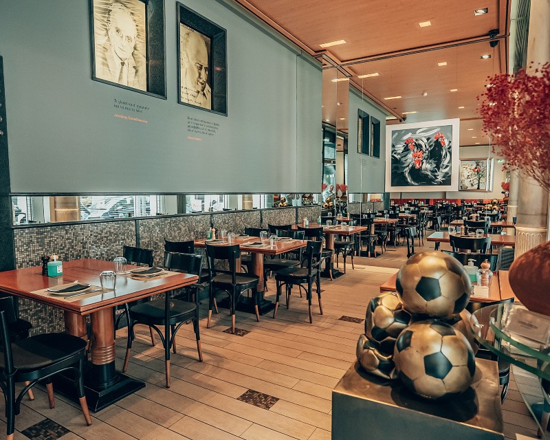 where locals eat in Athens - Interior of Athinaikon restaurant in Athens with wooden tables, wall art, and a warm atmosphere, known for traditional meze and ouzeri culture.
